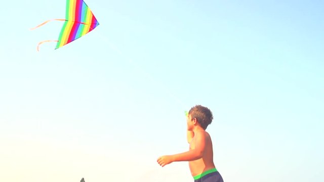 Little boy flying a kite on the beach. Happy kid playing with flying kite. Summer vacation concept. Slow motion 240 fps. Full HD 1080p. High speed camera