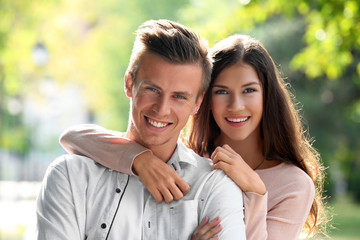 Fototapeta premium Portrait of beautiful young couple outdoors on blurred background