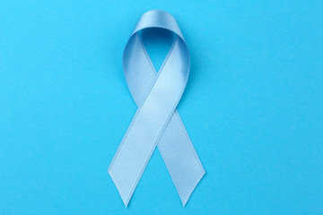 Light blue ribbon on color background. Prostate cancer concept