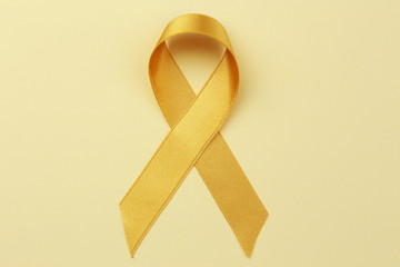 Golden ribbon on color background. Children cancer concept