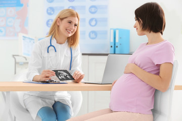 Obraz premium Doctor showing ultrasound photo to pregnant woman
