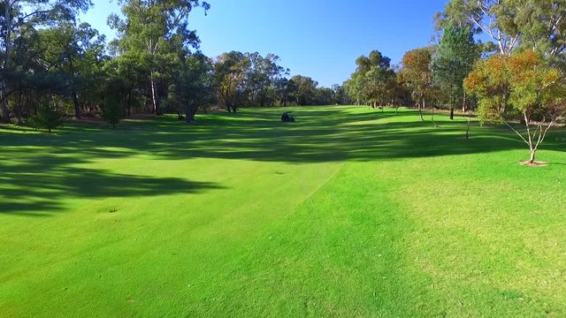 Drone aerial view of Golfers in Electric Golf Buggy with Caddy driving through Golf Course.
