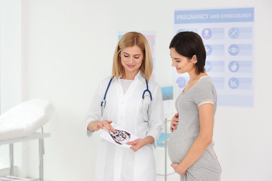 Doctor showing ultrasound photo to pregnant woman