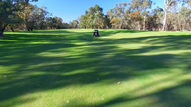 Drone aerial view of Golfers in Electric Golf Buggy with Caddy driving through Golf Course.
