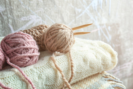 Knitting yarn and needles on pile of  plaids, closeup