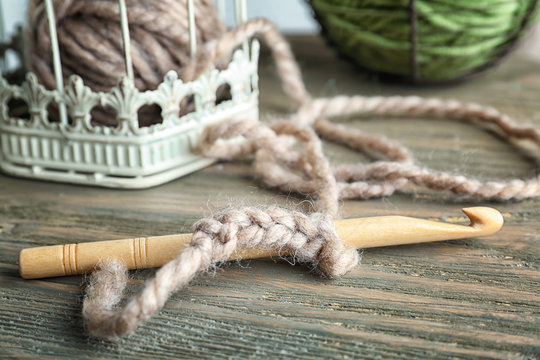 Closeup of hook with knitting yarn on wooden table