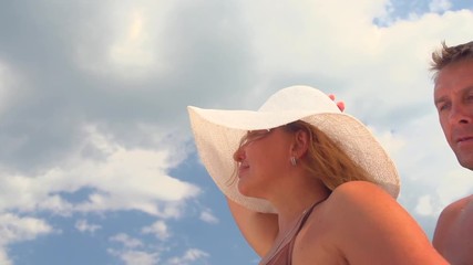 Happy loving middle-aged couple at the beach. Happy couple enjoying romantic vacation, man hugging his wife, kissing and smiling over blue sky. Slow motion 240 fps. Full HD 1080p