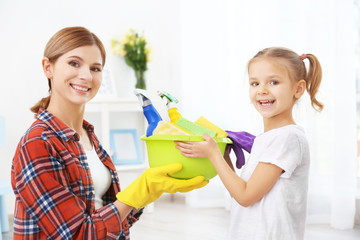 Little girl and her mother with cleaning supplies at home