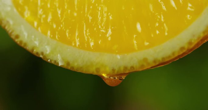 Close up or macro of a slice of orange, a drop of water falls in slow motion. The fruit gives off frescazza and juice filling. Concept of fresh fruit, cocktail, orange juice and Italian from Sicily.