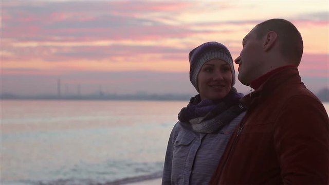 young couple walking on the beach at evening in winter.