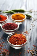 Aromatic spices in glass bowls on blue wooden background