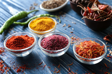 Aromatic spices in glass bowls on blue wooden background