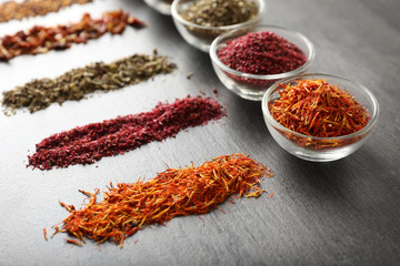 Various spices in glass bowls on grey table