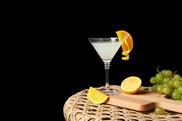 Tasty cocktail and fruits on wicker table and black background