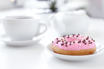 Delicious donut on saucer with cup of tea closeup