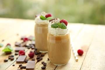 Tasty milk shake cocktails with coffee beans and chocolate on wooden table
