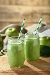 Tasty milk shake cocktails with spinach and apples on wooden table