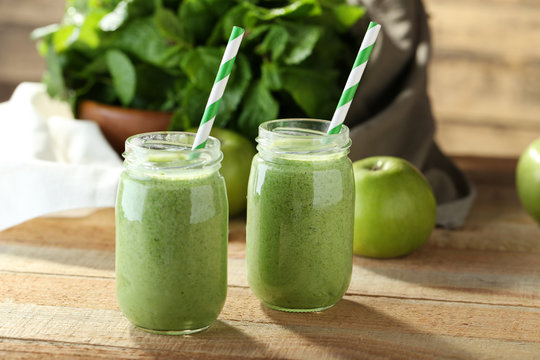 Tasty milk shake cocktails with spinach and apples on wooden table