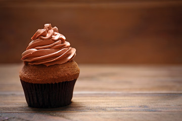 Tasty chocolate cupcake on wooden table