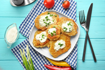 Plate with tasty potato pancakes for Hanukkah and some ingredients on wooden table