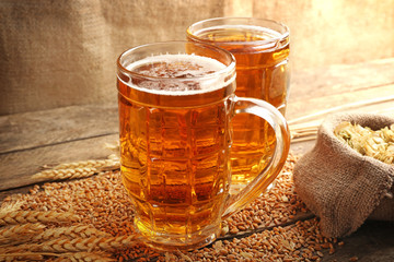 Glasses of beer and ingredients on wooden background