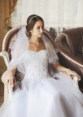 Beautiful bride sitting in vintage armchair