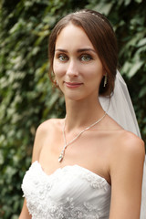 Beautiful bride on blurred green foliage background