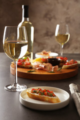 Tasty bruschetta served with white wine on table