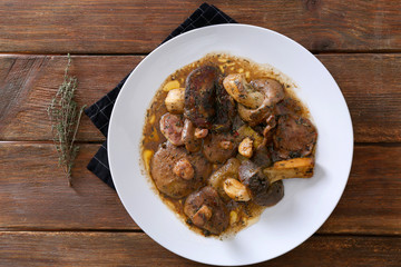 Plate with delicious mushrooms on wooden background