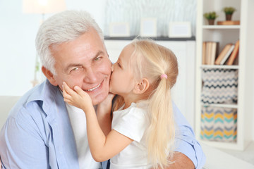 Cute little girl with grandfather in living room