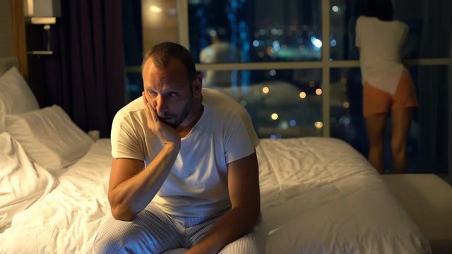 Sad, unhappy couple having sexual problems in bedroom at night
