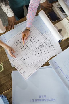 Overhead view of architects discussing blueprint in office