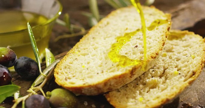 Genuine Italian organic oil cold pressed in slowmotion falls on organic bread. concept of nature and healthy food, healthy and natural. fresh olives and Tuscan Italian oil