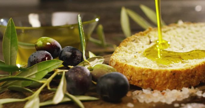 Genuine Italian organic oil cold pressed in slowmotion falls on organic bread. concept of nature and healthy food, healthy and natural. fresh olives and Tuscan Italian oil