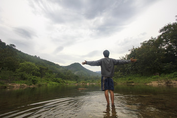 single young man stand on stone in river on his disappointed holiday : positive thinking concept (Khiriwong Fuit Village ,Nakhon Si Thammarat Province)