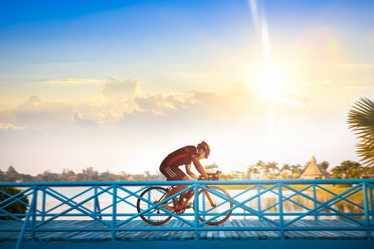 Man riding mountain bike on bridge trail at sunrise.