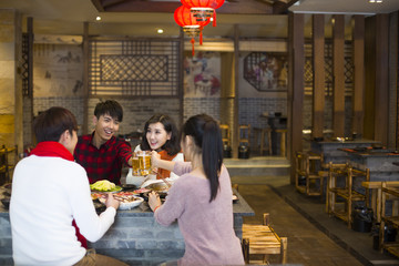 Young friends toast beer mugs in a restaurant