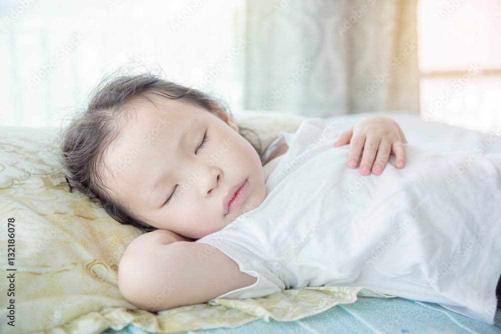 Wall mural Little Asian girl sleeping on bed at day time