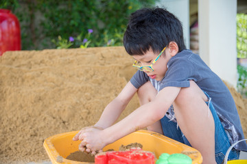 Young asian boy playing sand in sandbox