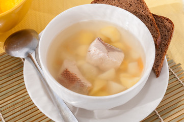 Fish soup in a white plate with black bread  