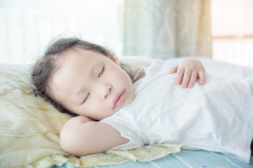 Obraz na płótnie Canvas Little Asian girl sleeping on bed at day time