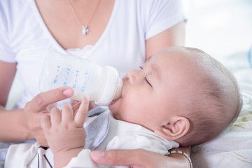 Little asian child drinking milk from bottle