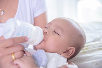 Obraz na płótnie Canvas Little asian child drinking milk from bottle