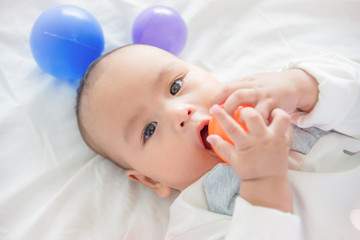 Little asian child lying on bed with ball