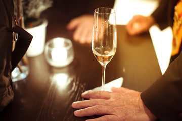 blurry background, white wine in hand of man on the table on din