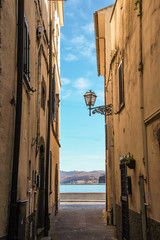 narrow alley of Marta fishermen burg  with landscape of Bolsena lake