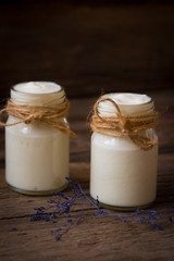 Yogurt in jar on the wooden table with purple dried plant
