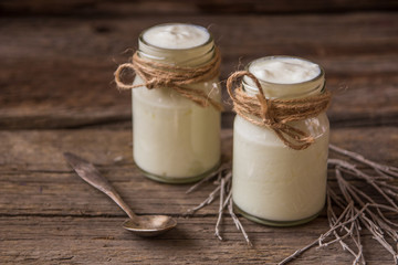 Yogurt in jars on the wooden table with dried plant