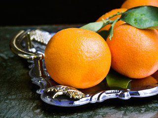 branch of ripe tangerine on a silver tray on dark background