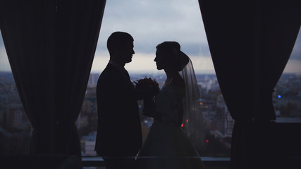 Silhouettes of the bride and groom on the background the city